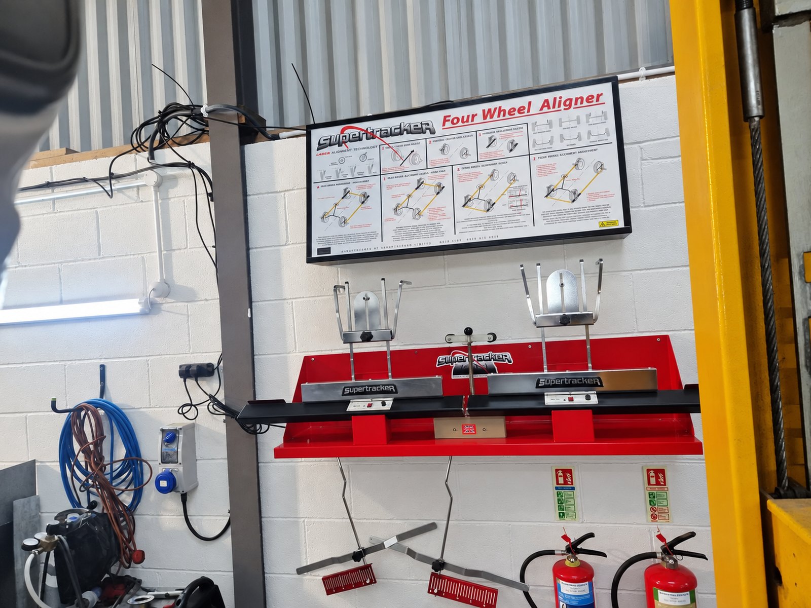 Supertracker four-wheel laser alignment equipment on the workshop wall