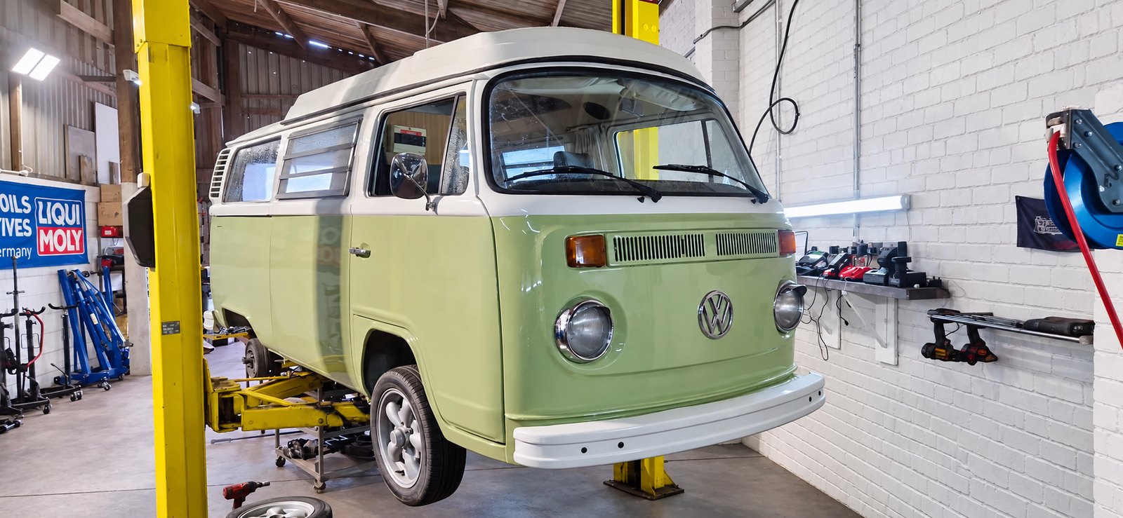 Classic VW camper van raised on a lift in the workshop